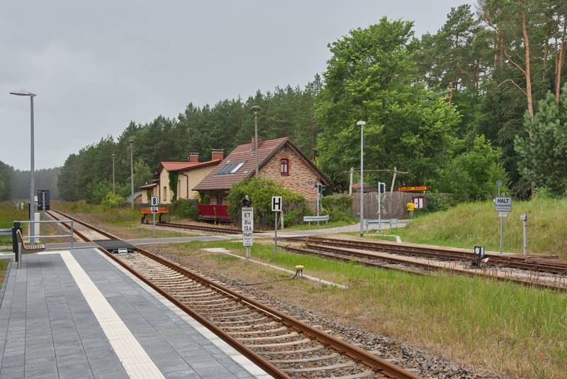 Blick auf den modernen Bahnsteig sowie den Bahnübergang von Zirtow.