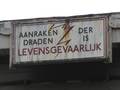905457, Afbeelding van het (mogelijk nog uit 1938 daterende) bordje "Aanraken der draden is levensgevaarlijk" op de kopse rand van één van de perronkappen (noordzijde) van het N.S.-station Utrecht C.S. (Centraal Station, Stationsplein) te Utrecht., Goosen, D.C., fotograaf