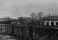156861, Afbeelding van enkele goederenwagens van de Staatsspoorwegen op het emplacement van het station Groningen van de Staatsspoorwegen te Groningen. Rechts een deel van de rijtuigloods, links een deel van het stationsgebouw en op de achtergrond de woning van de stationschef., Onbekend