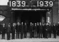 157426, Afbeelding van enkele genodigden, N.S.-directieleden en leden van het Eeuwfeest Comité Amersfoort voor de hoofdingang van het N.S.-station Amersfoort te Amersfoort ter gelegenheid van het 100-jarig jubileum van de Nederlandse Spoorwegen., Otto Fotobureau, fotograaf