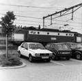 154538, Gezicht op een aantal geparkeerde auto's op de P+R-parkeerplaats bij het N.S.-station Driebergen-Zeist te Driebergen-Rijsenburg, met op de achtergrond de passerende electrische locomotief nr. 1306 (serie 1300) van de N.S., Nederlandse Spoorwegen, fotograaf