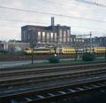 849414, Gezicht op de centrale voor de stadsverwarming van de PEGUS aan de Nicolaas Beetsstraat te Utrecht, vanaf hetoverlaadperron van het Expeditieknooppunt van de P.T.T. aan de Mineurslaan. Met op het emplacement van het Centraal Station de electrische locomotief nr. 1603 "Zutphen" (serie 1600) van de N.S. met dubbeldeksmaterieel (DDM)., Peeters, N.M., fotograaf/schilder