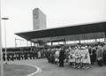 171109, Afbeelding van de aanwezigen bij de opening van het nieuwe N.S.-station Beverwijk, tijdens het hijsen van de vlaggen op het voorplein., Hessels, L. (Nederlandse Spoorwegen), fotograaf