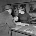 841305, Afbeelding van de informatrice in het inlichtingenbureau van het N.S.-station Den Haag H.S. te Den Haag., Hessels, L. (Nederlandse Spoorwegen), fotograaf