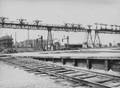 220185, Gezicht op de seinbrug aan de westzijde van het N.S.-station Amsterdam C.S. te Amsterdam, met enkele waterkolommen en geheel links het seinhuis op het Westelijk Eiland., Onbekend