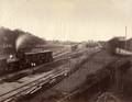 156913, Gezicht op het emplacement van het station Groningen van de Staatsspoorwegen te Groningen. Links rangeert stoomlocomotief nr. 64 (serie 21-78, later vernummerd tot nr. 752 en opgenomen in de serie 701-775) van de Staatsspoorwegen. Op de achtergrond van links naar rechts de locomotiefloods, de goederenloods, het stationsgebouw en de rijtuigloods., Onbekend
