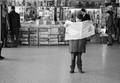 835229, Afbeelding van een klant in de krantenkiosk op het Centraal Station (Stationsplein, N.S.-station Utrecht C.S.), verdiept in een Italiaanse krant., Sitsen, J.M.A., fotograaf