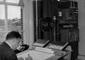 156458, Afbeelding van de treindienstleider in de Centrale Radio Verkeersleidingspost (CRVL-post) in het N.S.-station Usquert te Usquert.