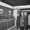 858592, Afbeelding van de tentoonstelling ter gelegenheid van de opening van het nieuwe N.S.-station Beverwijk, met commissaris van de koningin dr. M.J. Prinsen, president-directeur ir. J. Lohmann en burgemeester J.G.S. Bruinsma die te tentoonstelling bezoeken., Hessels, L. (Nederlandse Spoorwegen), fotograaf